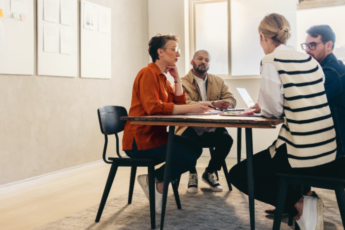 Réunion entre 4 collègues dans un bureau autour d'une table avec un ordinateur